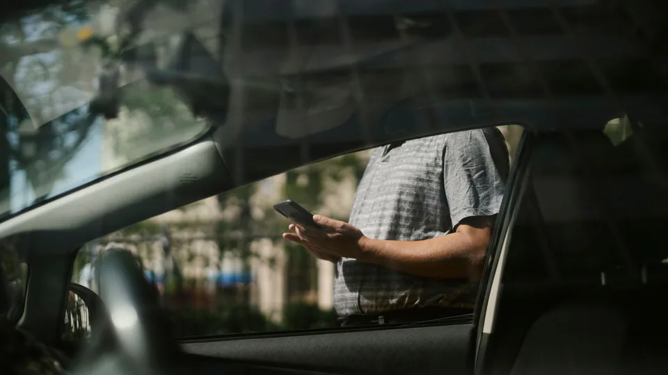 Traveller using a ride-hailing app beside a car in China