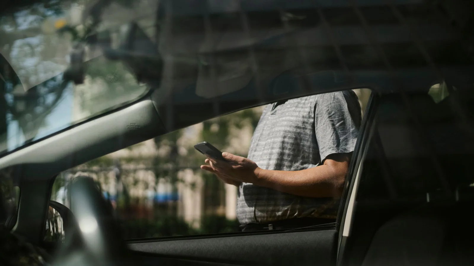 Traveller using a mobile ride-hailing app beside a car in China