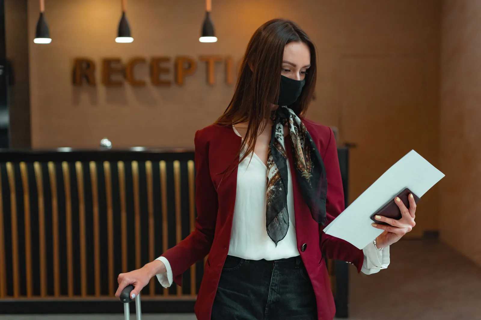 Hotel guest holding a passport and check-in papers beside a reception desk