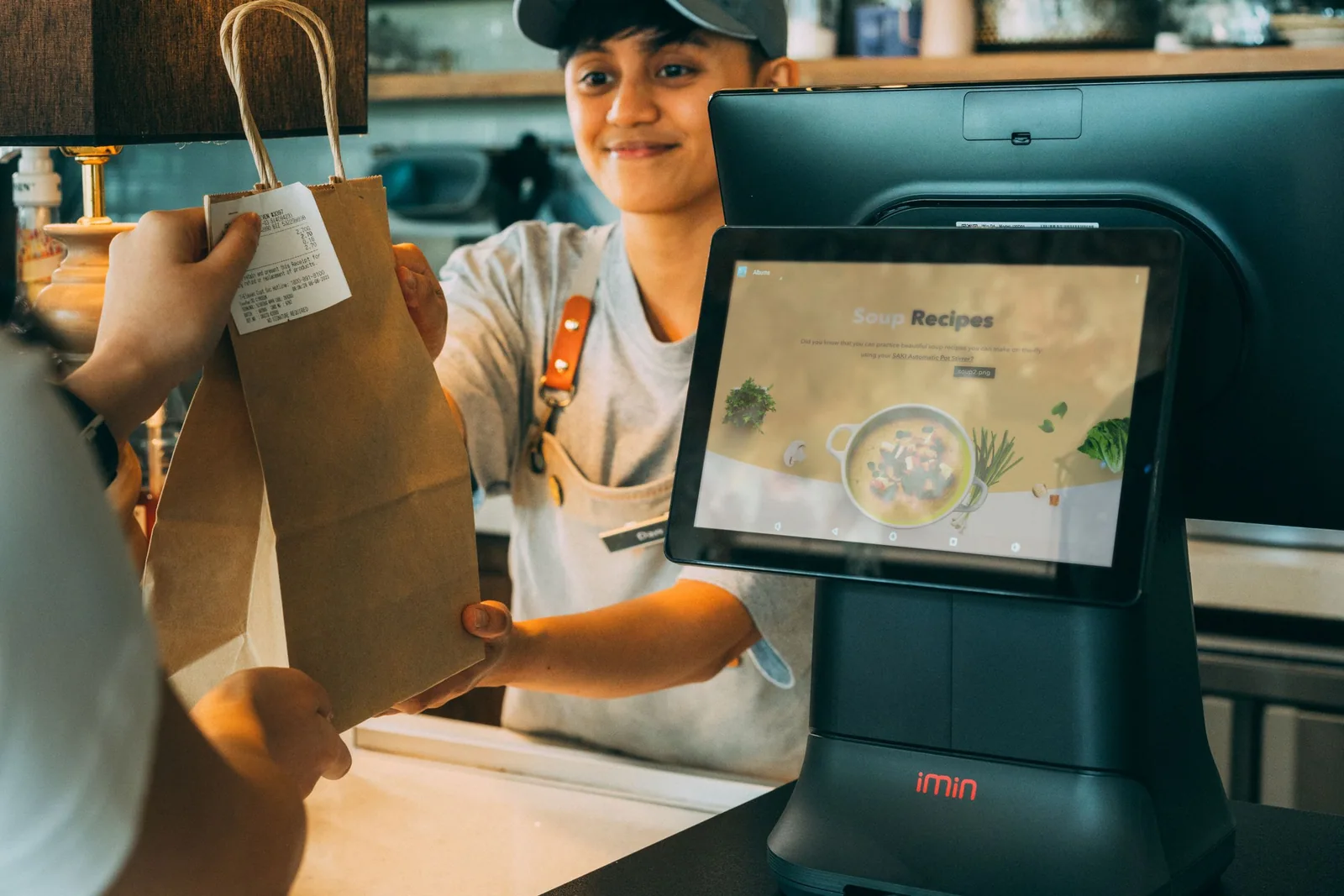 Cashier handing a shopping bag and receipt to a customer at checkout