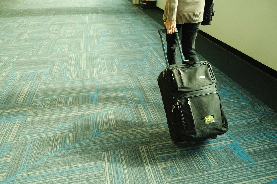 Traveller walking through an airport corridor with cabin luggage